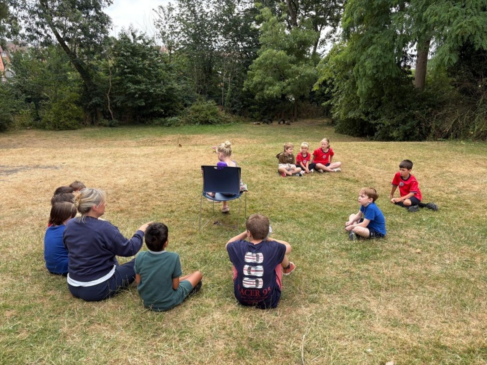 Children sitting in a circle on the grass for an outdoor session