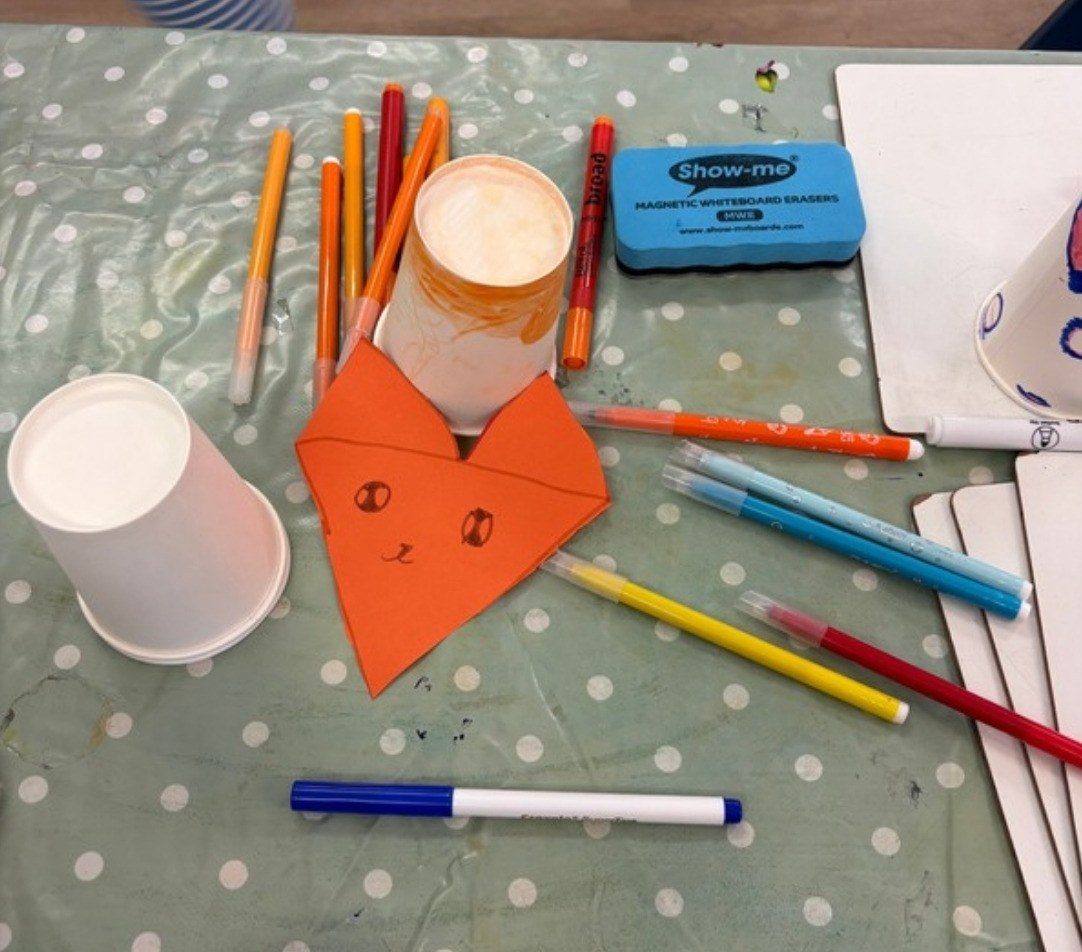 Paper cups, pens and an orange paper fox ready for crafting